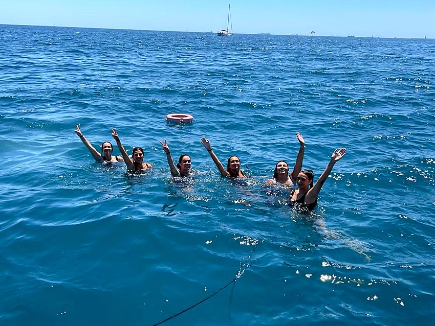 Grupo bañándose junto al velero fondeado